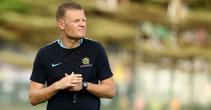 Joseph Gombau standing on a football field wearing a black and yellow tracksuit