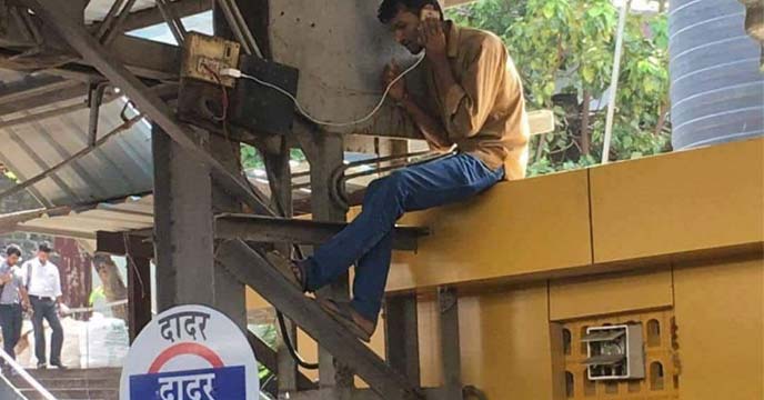 A man charging his mobile phone at a railway station in India
