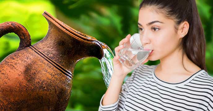 Young Indian girl drinking water from an earthen pitcher