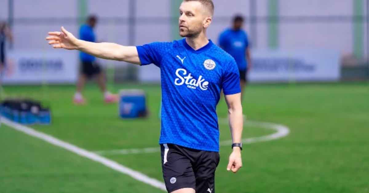 Image of Mumbai City FC Coach Petr Kratky, a man wearing a team tracksuit and cap, standing on a football field with a determined expression